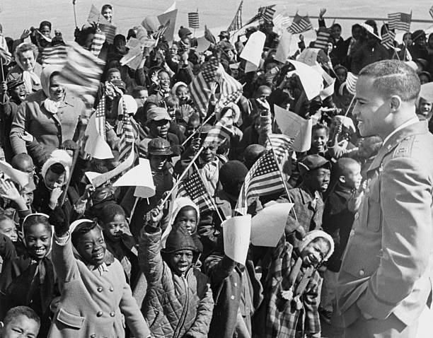 Dwight jeune devant une foule d'écoliers arborant des drapeaux américains.