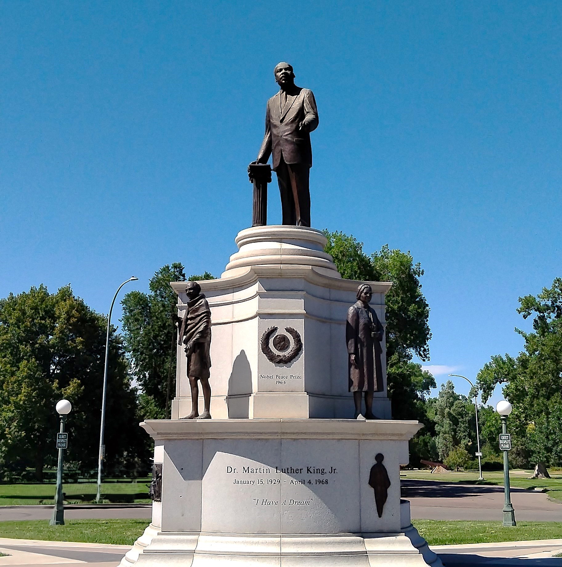 Monument avec Martin Luther King au sommet, Gandhi et Rosa Parks en dessous. Parc en arrière-plan.