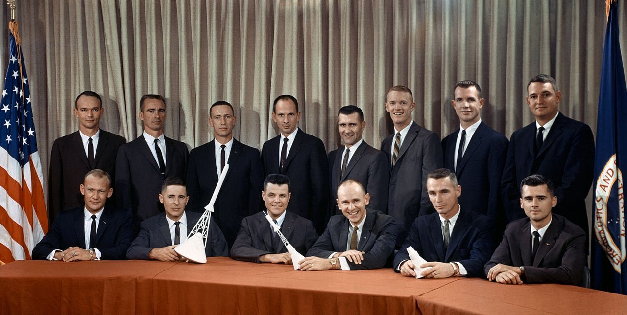 Photo de classe de 14 astronautes. Drapeaux américain et de la NASA en fond.